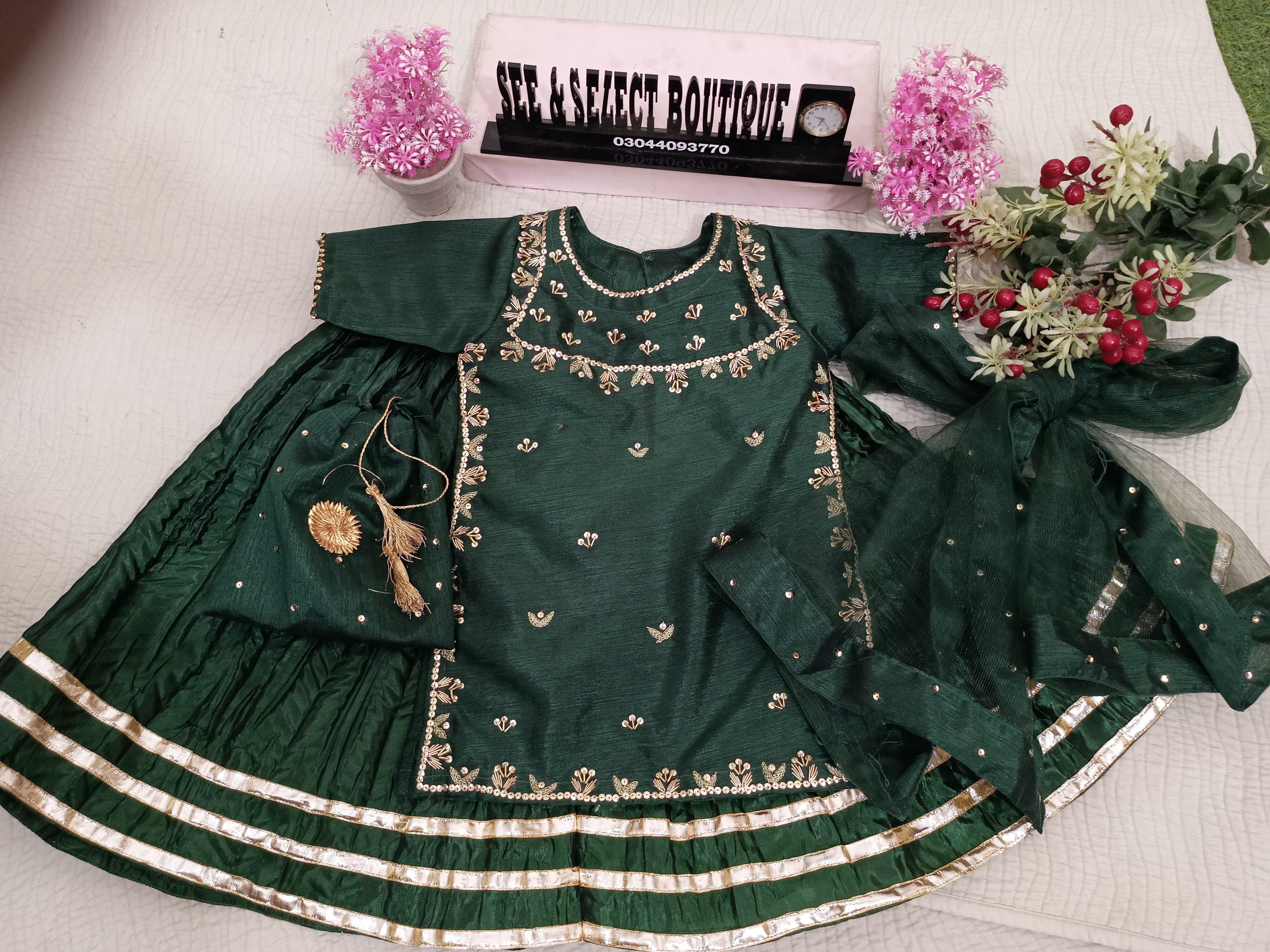 Green embroidered garment on a mannequin with decorative elements on a light background