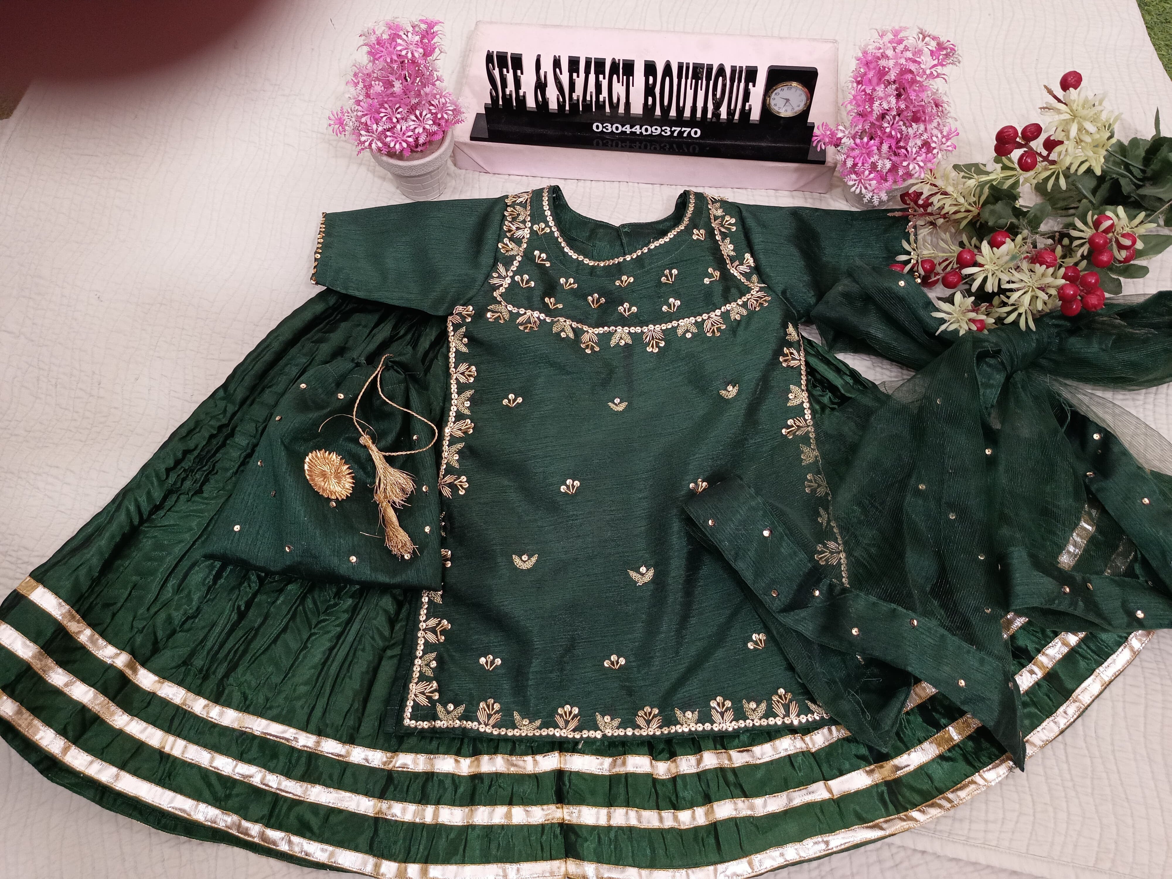 Green embroidered outfit on a mannequin with decorative elements on a light background