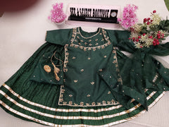 Green embroidered outfit on a mannequin with decorative elements on a light background